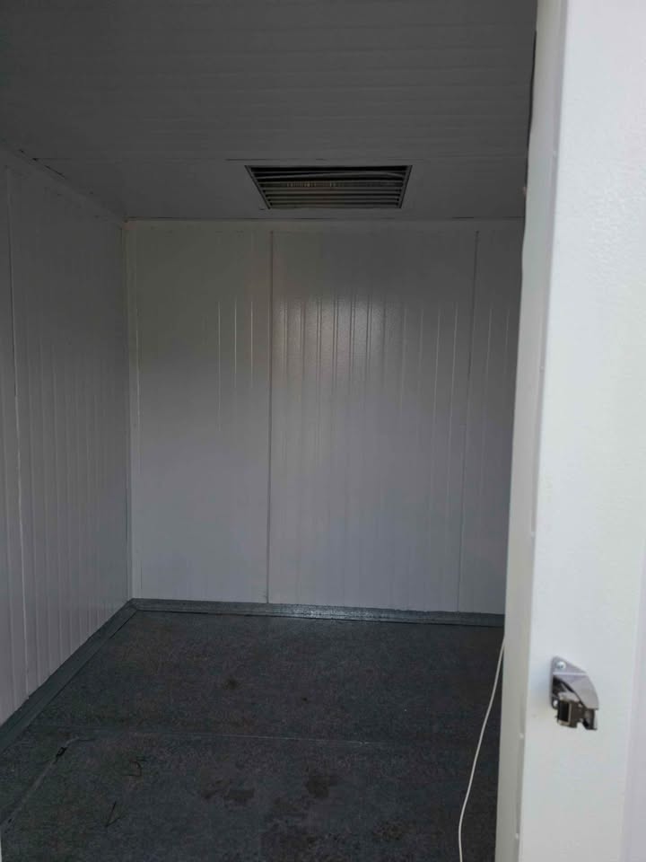 Inside an empty walk-in: white panel walls and the ceiling grille