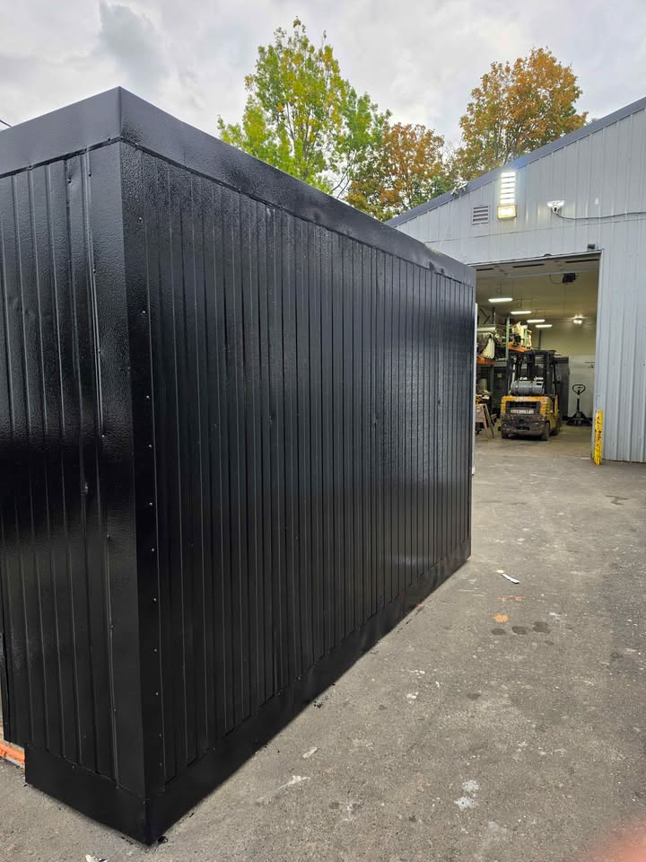 A black walk-in freezer box in front of the Coolers & More shop bay